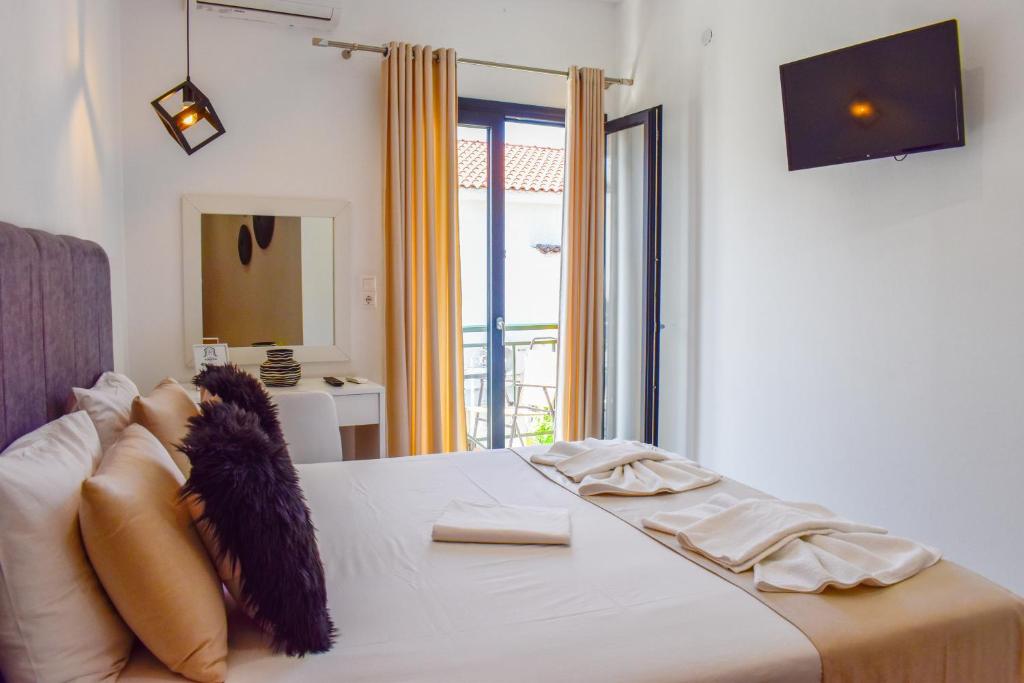 a bedroom with a large white bed with a window at Albertoshouse in Skiathos Town