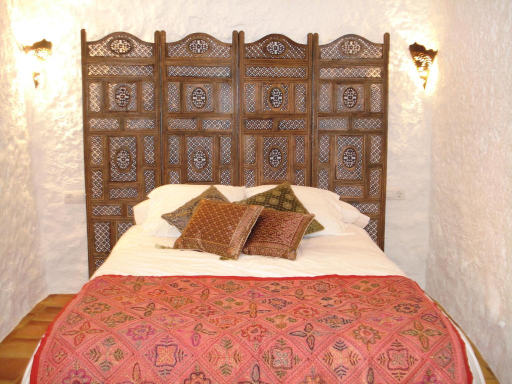 1 dormitorio con 1 cama grande y cabecero de madera en Cueva de La Alegría, en Huéscar