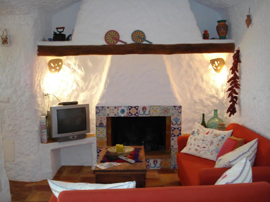 sala de estar con chimenea y TV en Cueva de La Alegría, en Huéscar