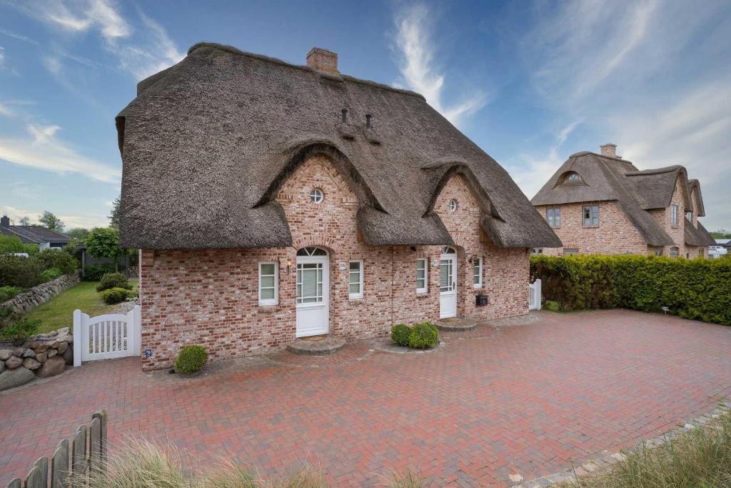 a large brick house with a thatched roof at Reetdachhaus Waterküken Waterküken in Süderhöft