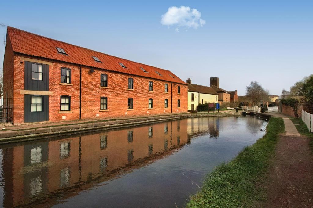 a brick building next to a river next to a building at Canalside Wharf in Retford