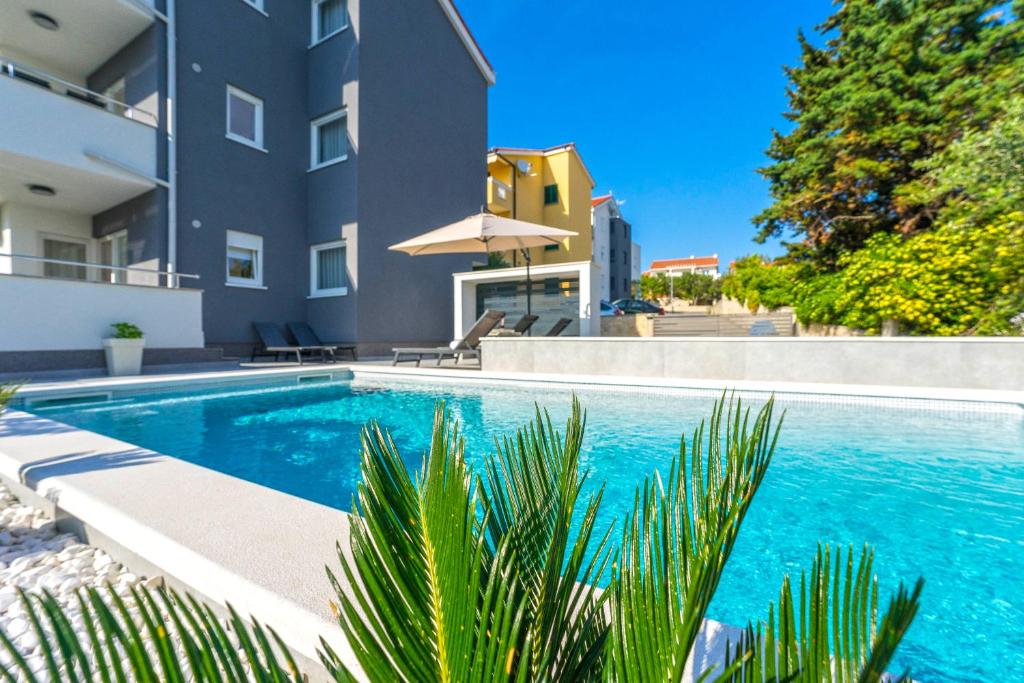 a swimming pool in front of a building at Summer Breeze Pool Apartments in Novalja