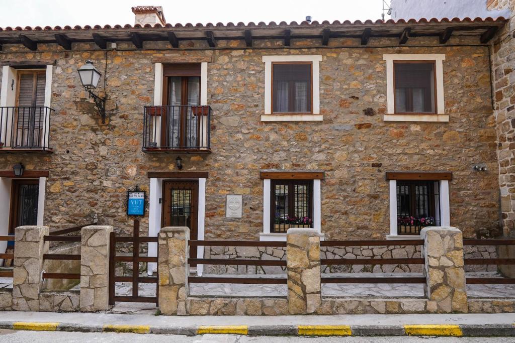 un antiguo edificio de piedra con ventanas y una valla en CASA MÁXIMO, en Puertomingalvo