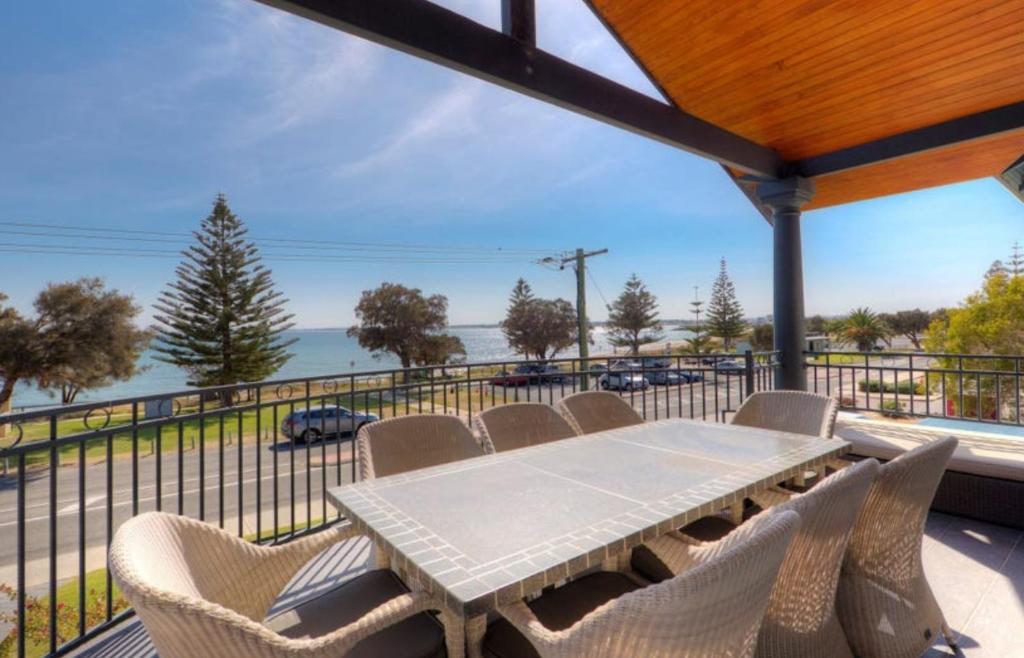 een tafel en stoelen op een balkon met uitzicht op de oceaan bij Beachfront Family Favourite Home with Pool & Views in Mandurah