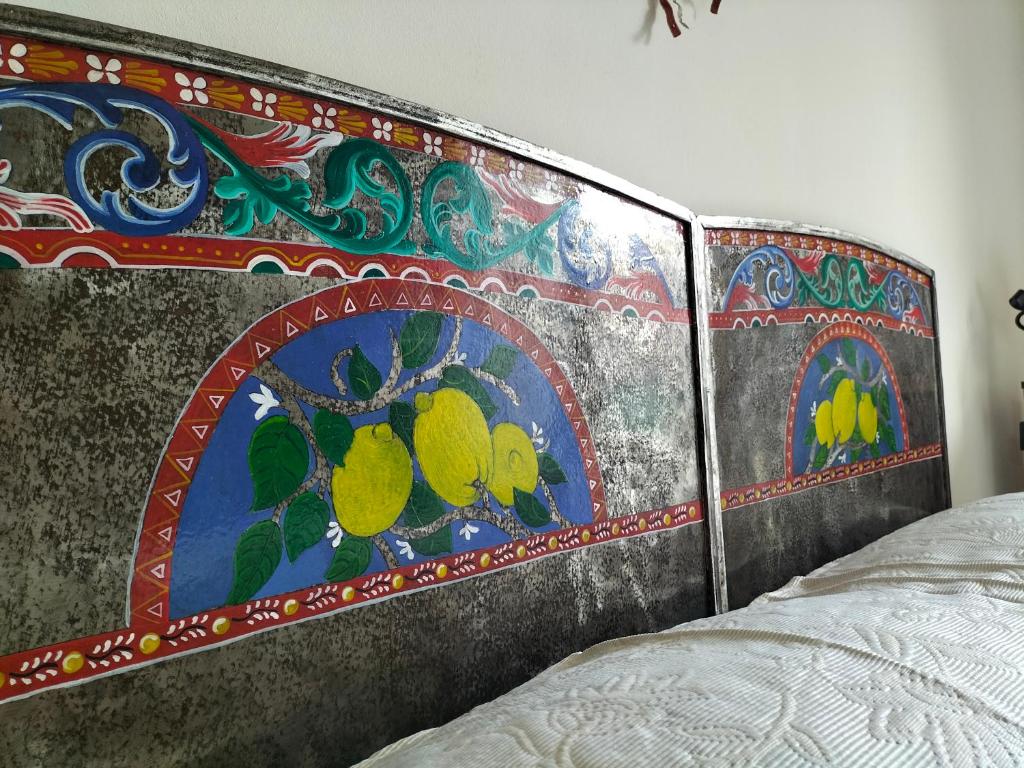 a bed with a head board with a painting on it at B&B Chapo in Catania