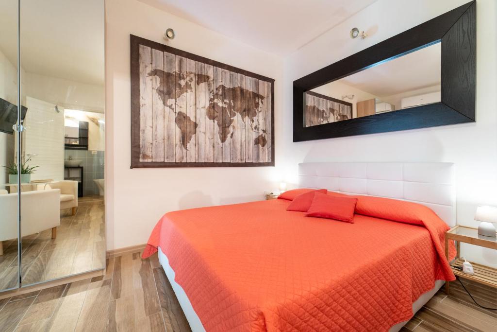 シラクーサにあるCasa Borbonica Cozy Apartment in Ortigia GROUND FLOORのベッドルーム1室(オレンジのシーツと鏡付きのベッド1台付)