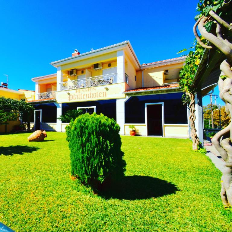 a building with a bush in front of a yard at Pfaffenhofen in Nea Vrasna