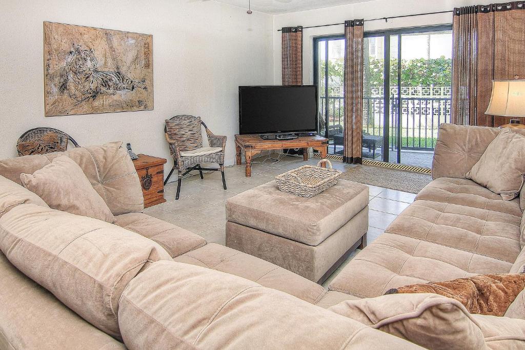 a living room with a couch and a flat screen tv at Belleair Sands 107 in Clearwater Beach