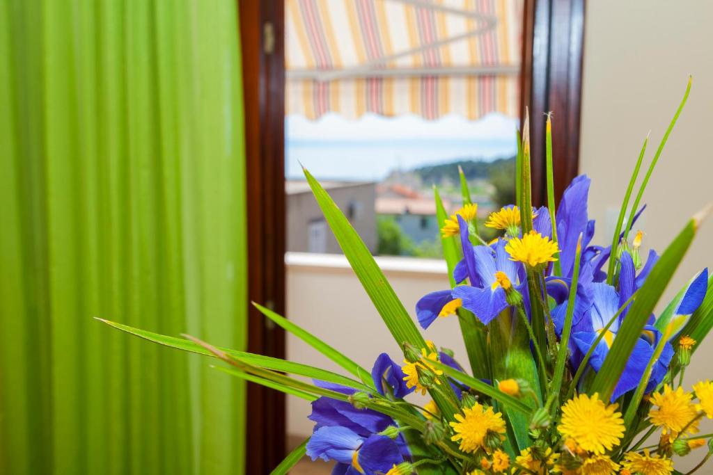 a vase of flowers in front of a mirror at Apartmani Centar Makarska in Makarska