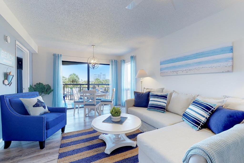 a living room with a white couch and blue chairs at Gulf Strand Resort 308 in St Pete Beach