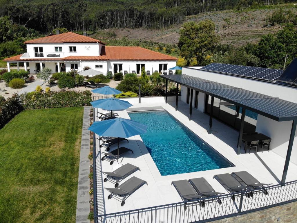 an aerial view of a house with a swimming pool with umbrellas at Casa Carvalhal in Góis