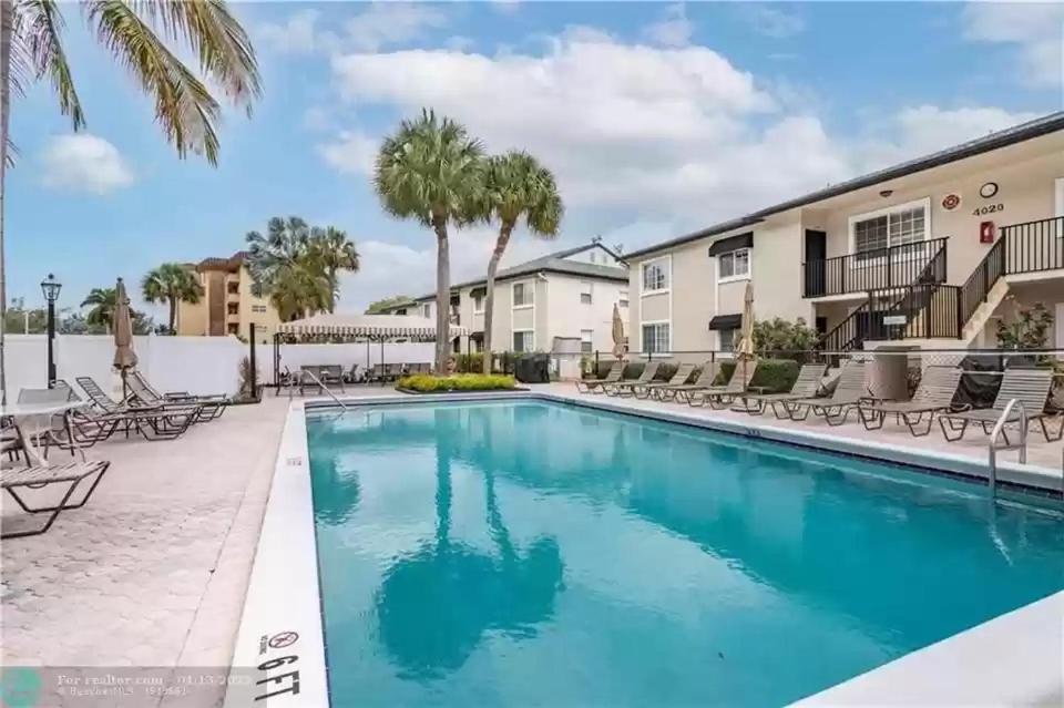 a pool with chairs and palm trees at a apartments at lovely 2BED 2BA vacation rental near the Beach in Pompano Beach