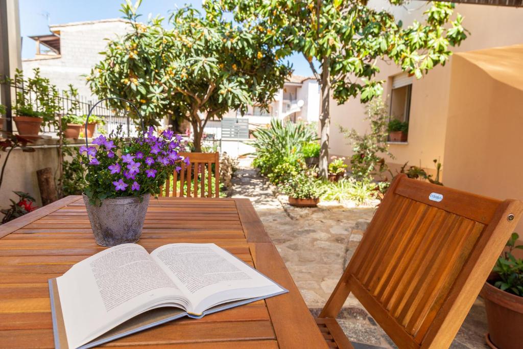 ein offenes Buch auf einem Holztisch mit einem Stuhl und Blumen in der Unterkunft Appartamenti Nonna Rosa in Santa Maria Navarrese
