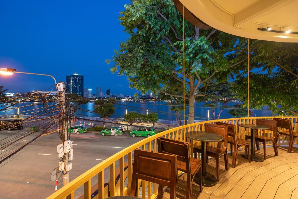 a balcony with tables and chairs and a view of a city at Dana Pearl Riverside Condotel in Danang