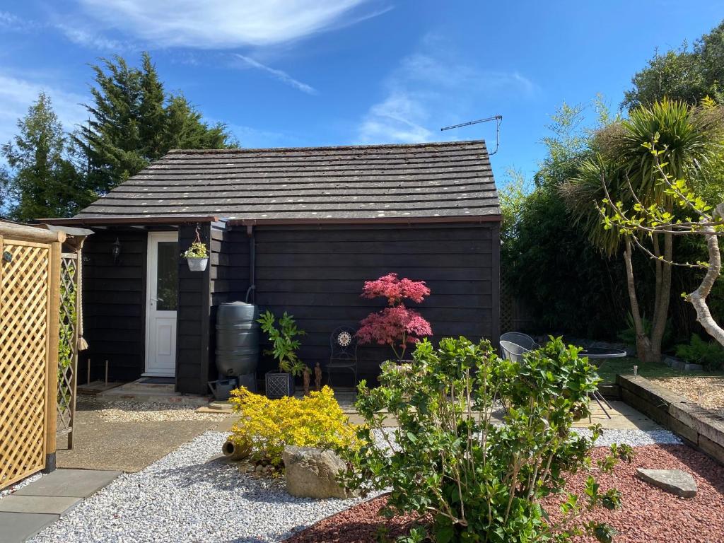 a small black shed with flowers in a garden at Self catering private annex near Ferndown in Ferndown