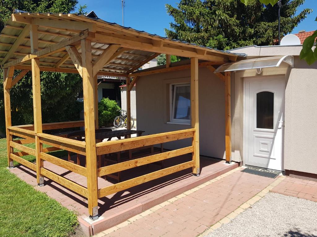 a wooden pergola with a table on a patio at Rezeda Apartman in Gárdony