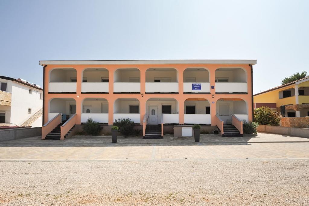 un gran edificio con grandes ventanas en un aparcamiento en Apartmani Dragičević, en Vir