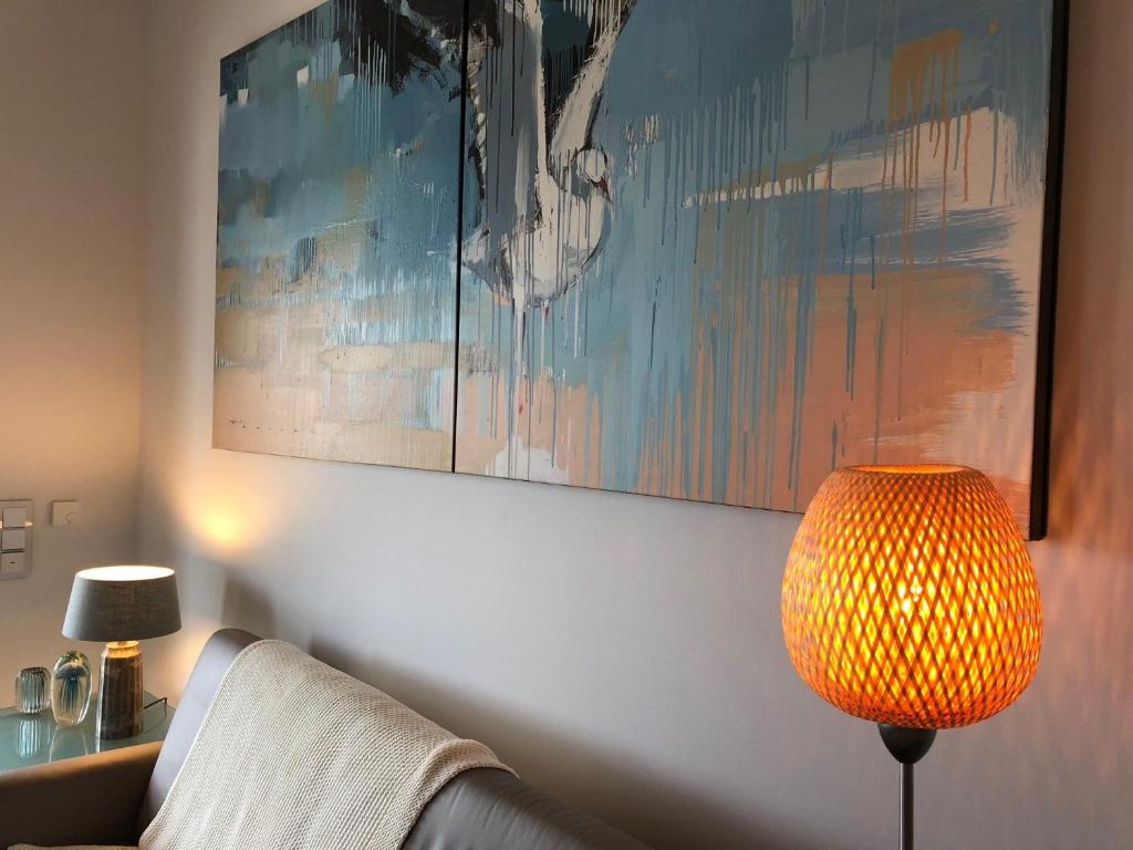 een woonkamer met een lamp en een schilderij aan de muur bij Penthouse 7 Heaven Nordsee Park Dangast in Dangast