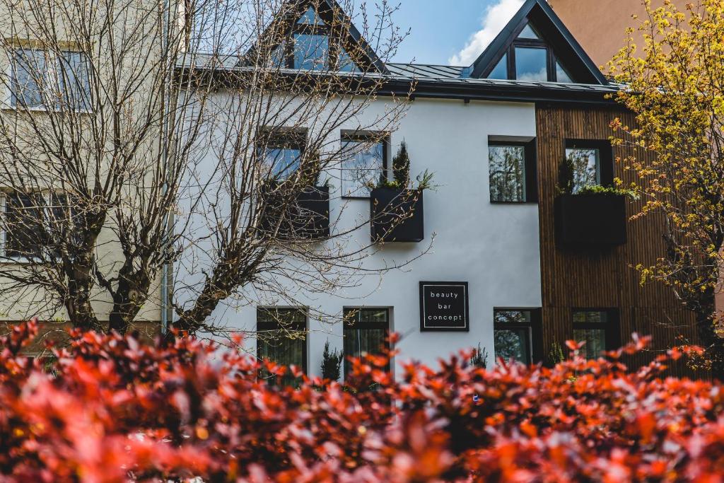 una casa blanca con flores rojas delante en beauty bar concept, en Žilina