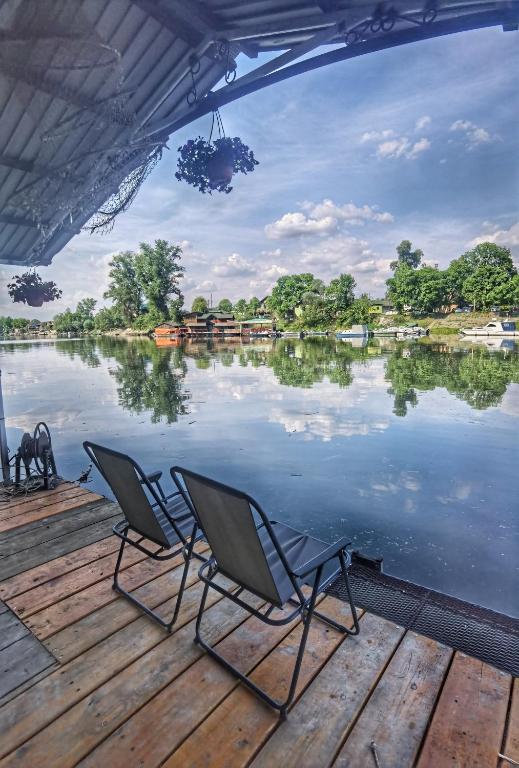 two chairs sitting on a dock next to a lake at Splav Ljubavno Ostrvo in Čerević