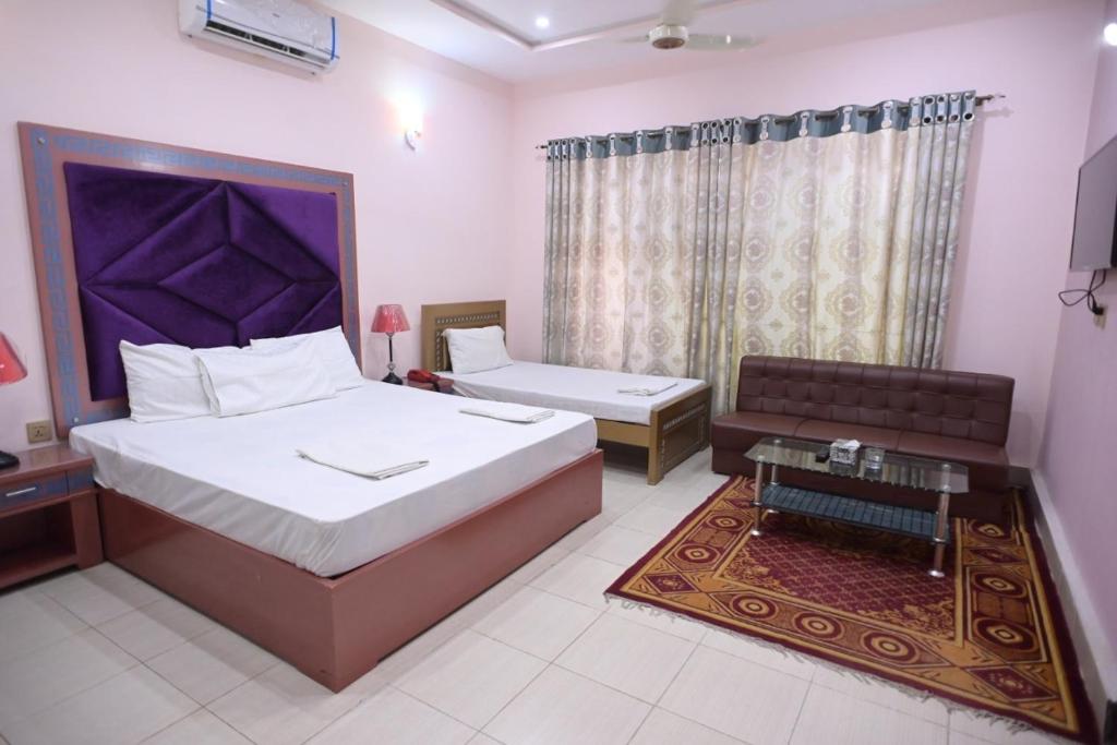 a bedroom with a bed and a couch and a table at Hotel Shaheen Continental Multan in Multan