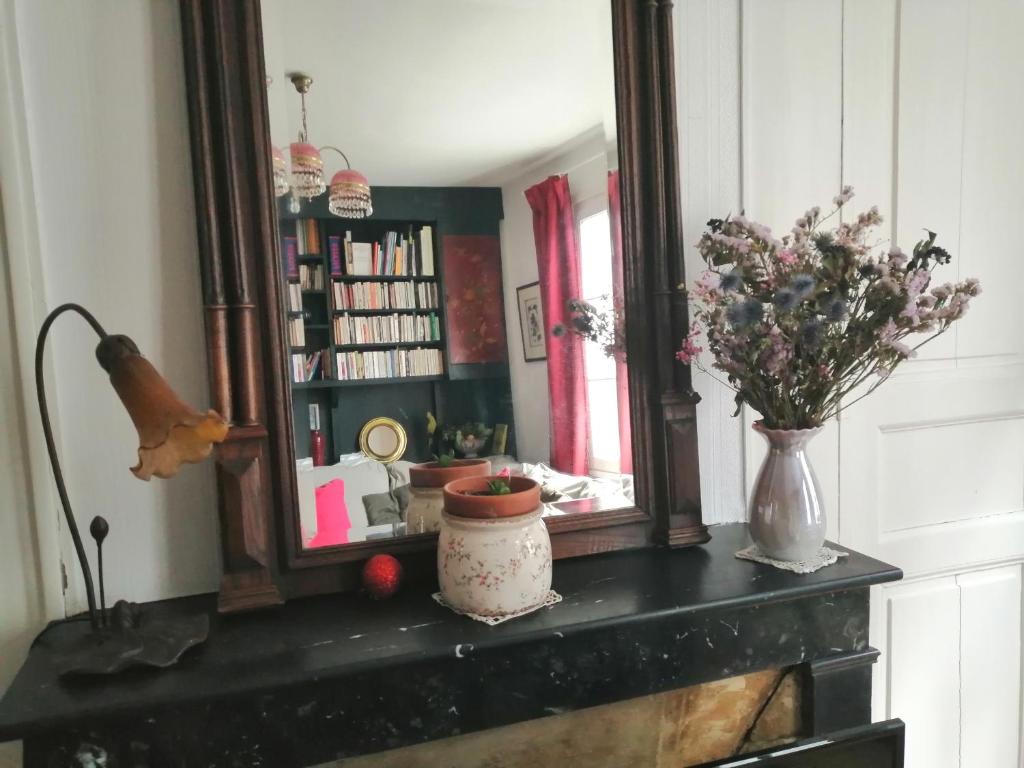 a mirror and a vase with flowers on a fireplace at La Bonne Etoile, près Giverny in Vernon