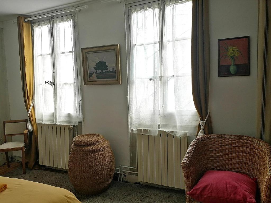 a bedroom with two windows and a bed and a chair at La Bonne Etoile, près Giverny in Vernon