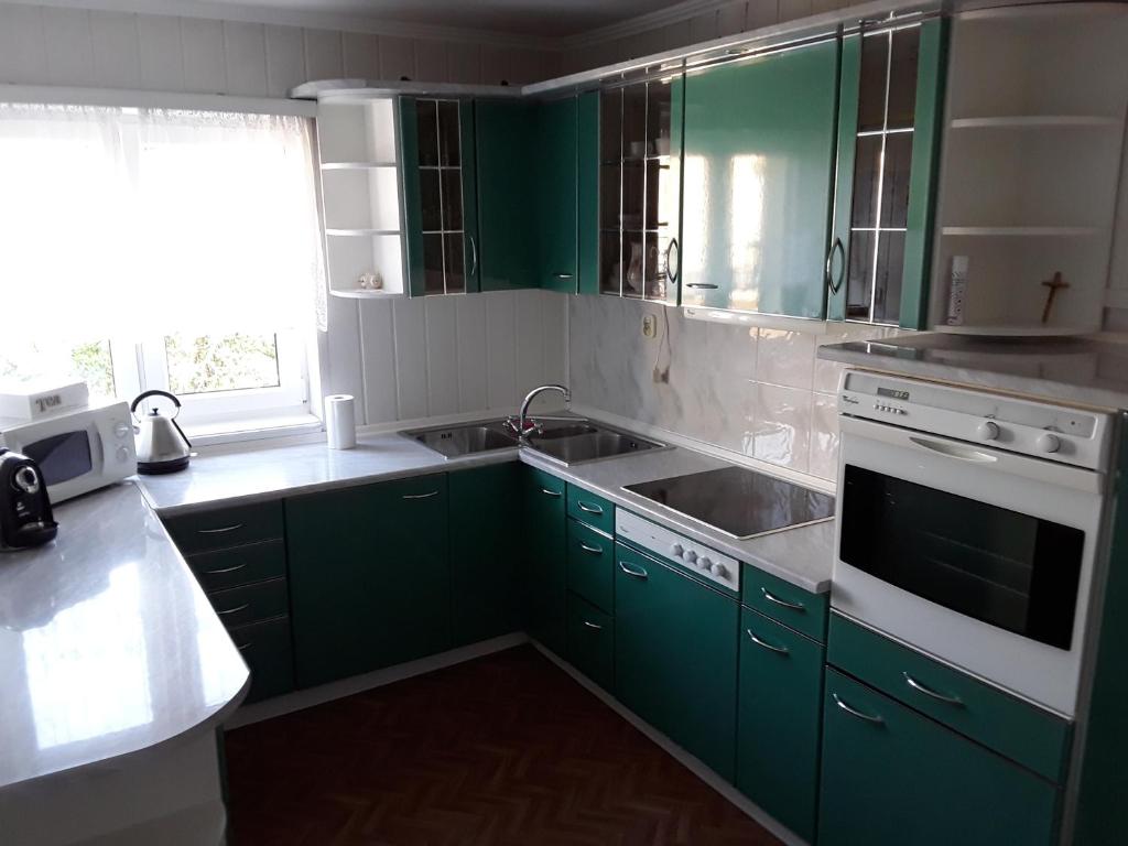 - une cuisine avec des placards verts et un évier dans l'établissement Apartament Nad Bałtykiem, à Świnoujście