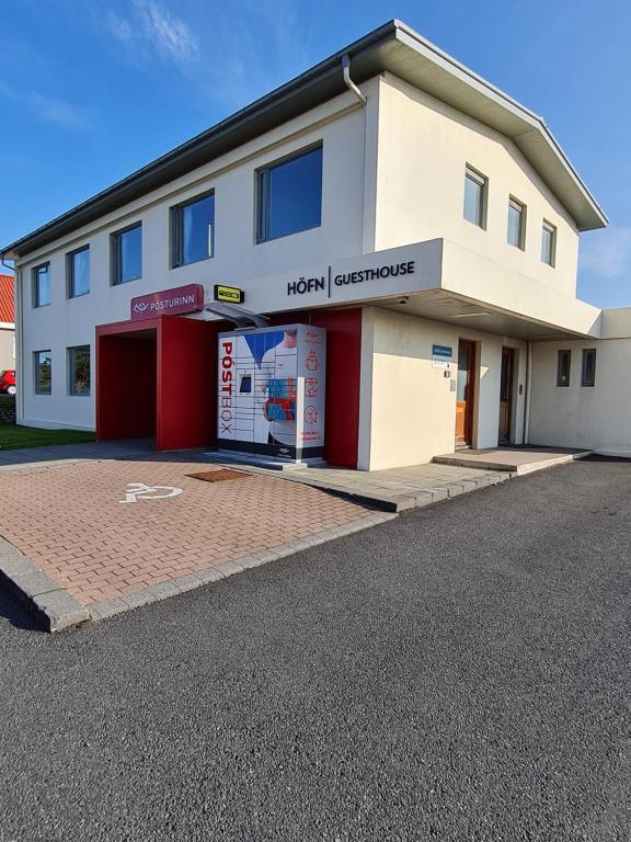 un gran edificio blanco con puertas rojas y un edificio en Höfn Guesthouse, en Höfn