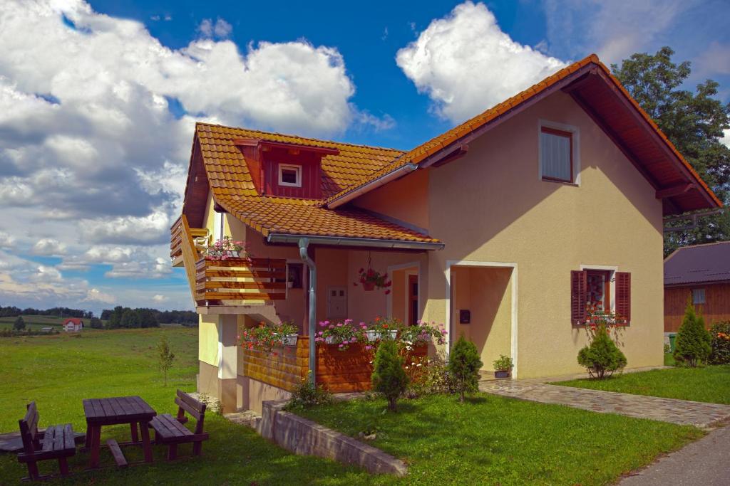 een klein huis met een groen veld en wolken in de lucht bij Apartment Ivan in Smoljanac