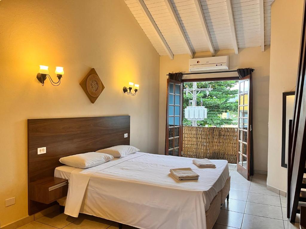 een slaapkamer met een groot bed en een raam bij Delphin Apartamento 8 in Ilhabela