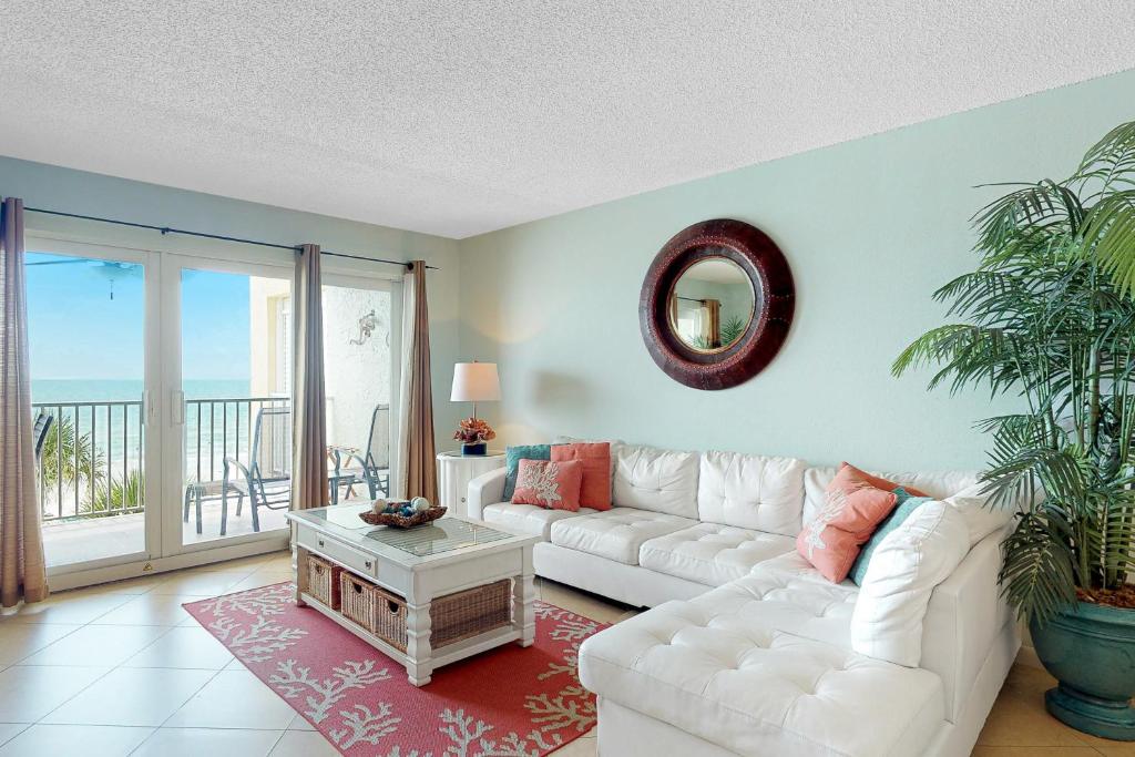 a living room with a white couch and a balcony at Ram Sea I 206 in St Pete Beach