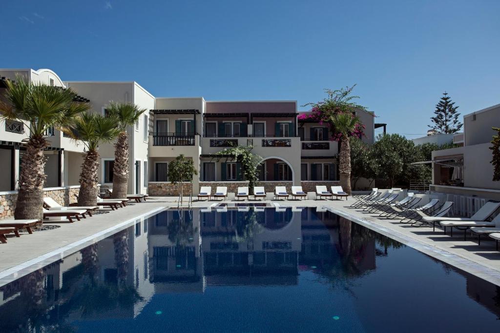 a swimming pool with lounge chairs and a building at Rose Bay Hotel in Kamari