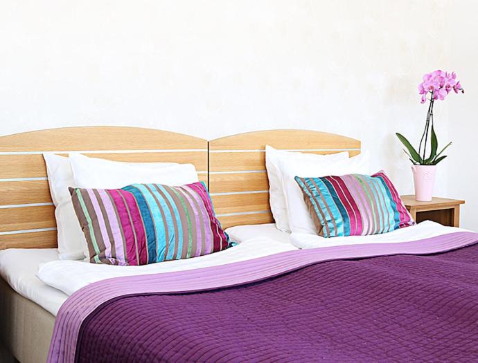 a bed with purple sheets and pillows and a vase with flowers at Hotell City in Härnösand