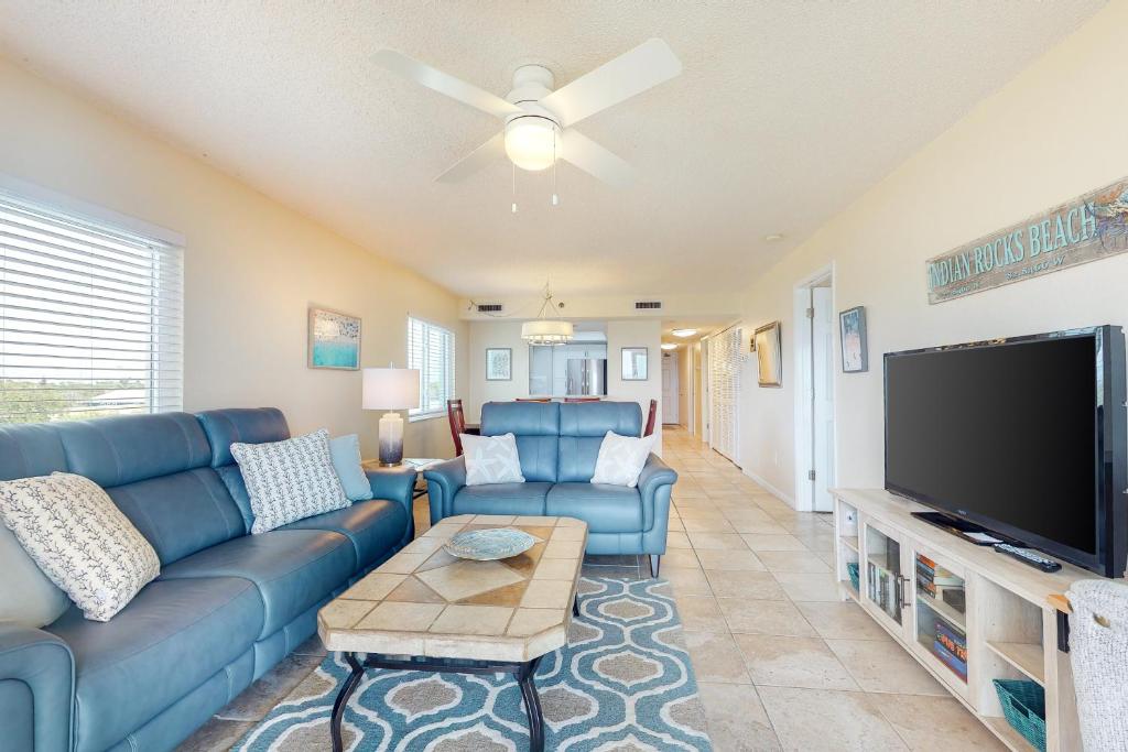 ein Wohnzimmer mit einem blauen Sofa und einem Flachbild-TV in der Unterkunft Sand Castle North 404 in Clearwater Beach