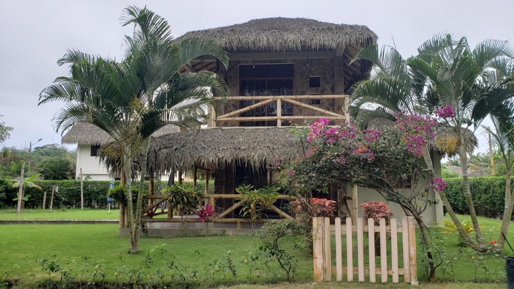 a house with a thatch roof and a fence at Casa vacacional campestre cerca de la playa in Santa Elena