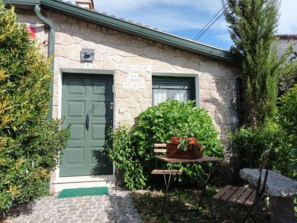 eine grüne Tür in einem Steinhaus mit einem Tisch in der Unterkunft Senda Verde do Salnés in Portas