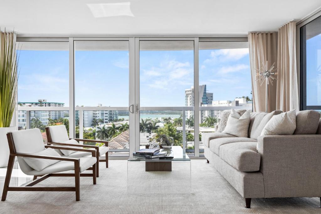uma sala de estar com um sofá e cadeiras e janelas grandes em Bay Harbor One Vacation em Miami Beach