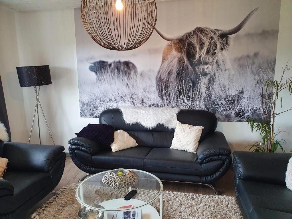 a living room with a black leather couch and a bull painting at Schöne Aussicht in Nettersheim