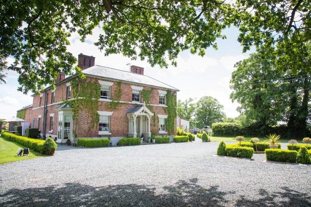 a large brick house with a driveway at Willington Lodge in Hanmer