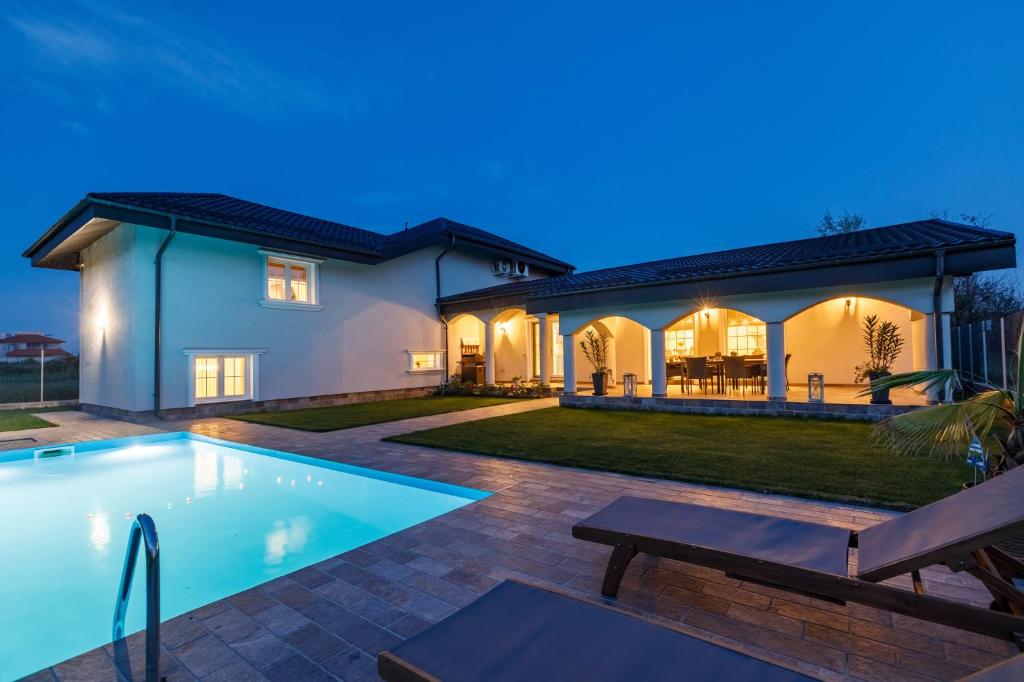 a villa with a swimming pool at night at Pool House Mamaia in Mamaia Nord