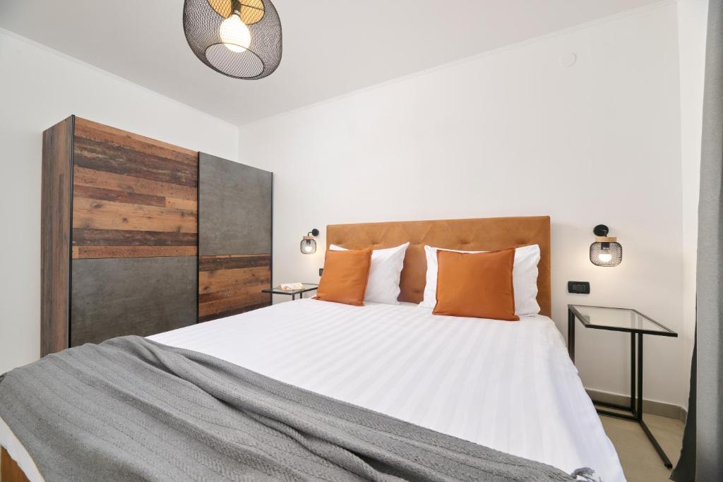 sypialnia z dużym białym łóżkiem z pomarańczowymi poduszkami w obiekcie Apartments Dolcea w mieście Umag