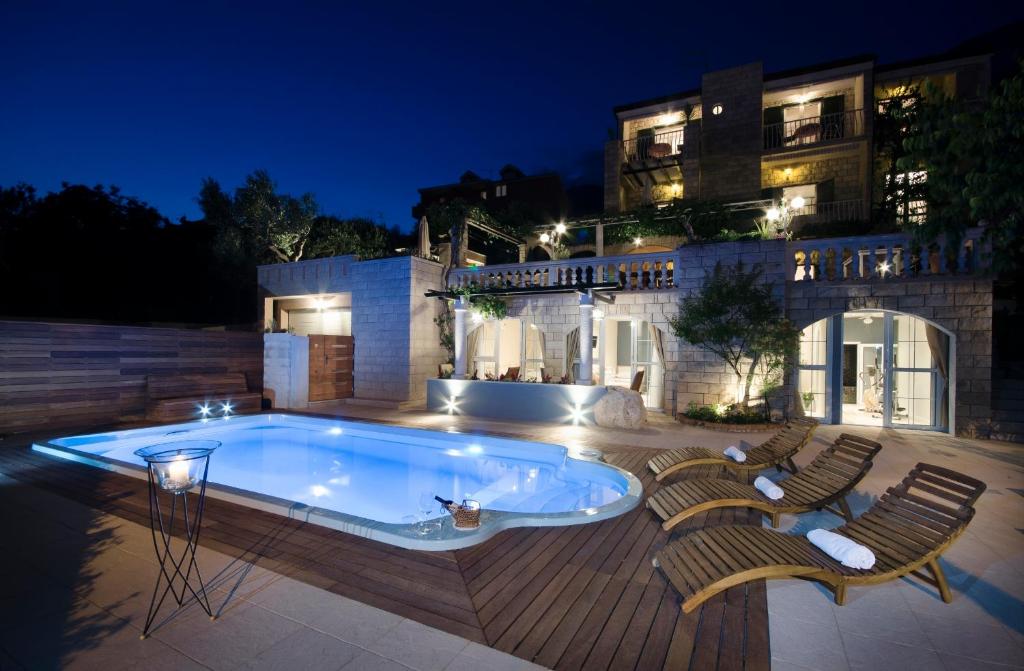 a swimming pool with chairs and a building at night at Villa Bougenvilia Tomas in Tučepi