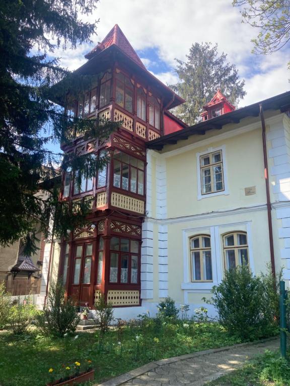 une grande maison blanche avec un toit rouge dans l'établissement Vila Flavia, à Sinaia