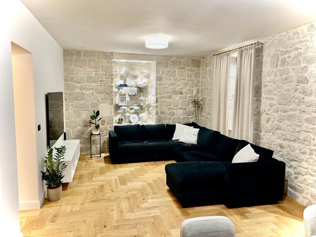 uma sala de estar com um sofá preto e uma parede de pedra em Adora Luxury Apartment em Split
