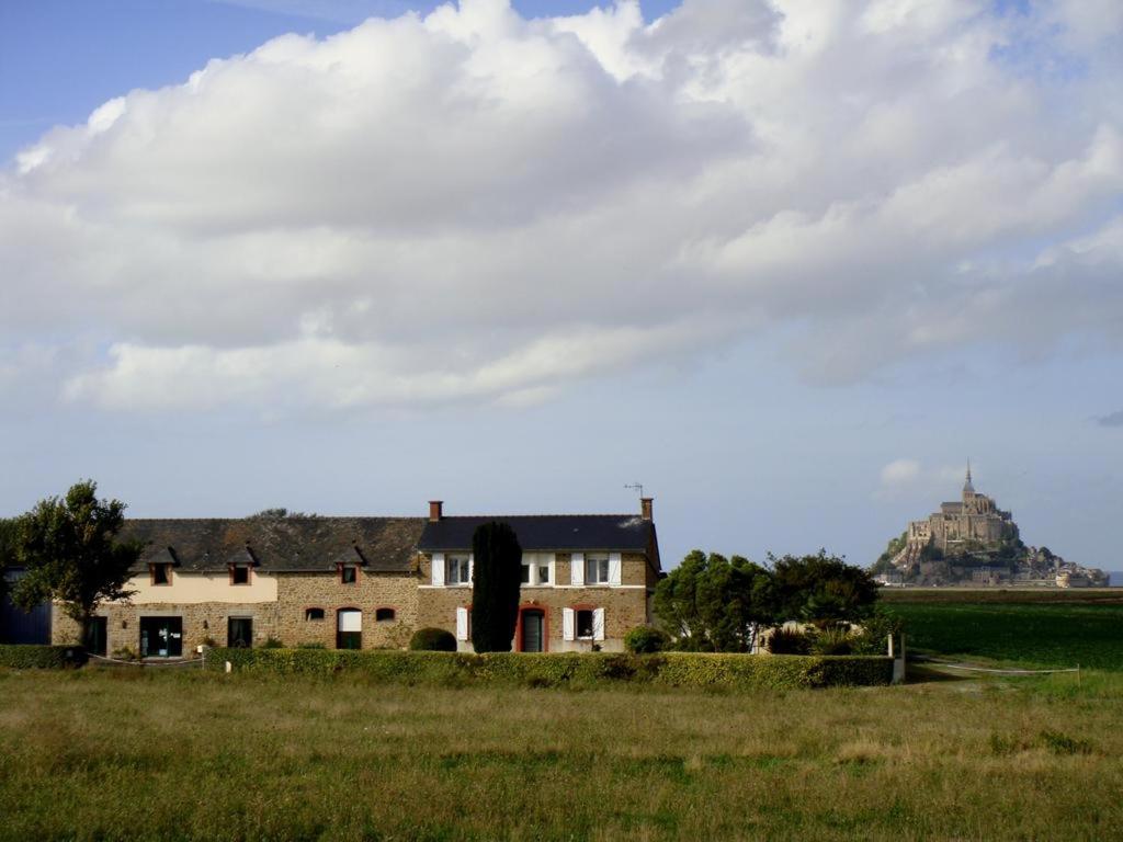 a house in a field with a hill in the background at La Jacotière in Ardevon