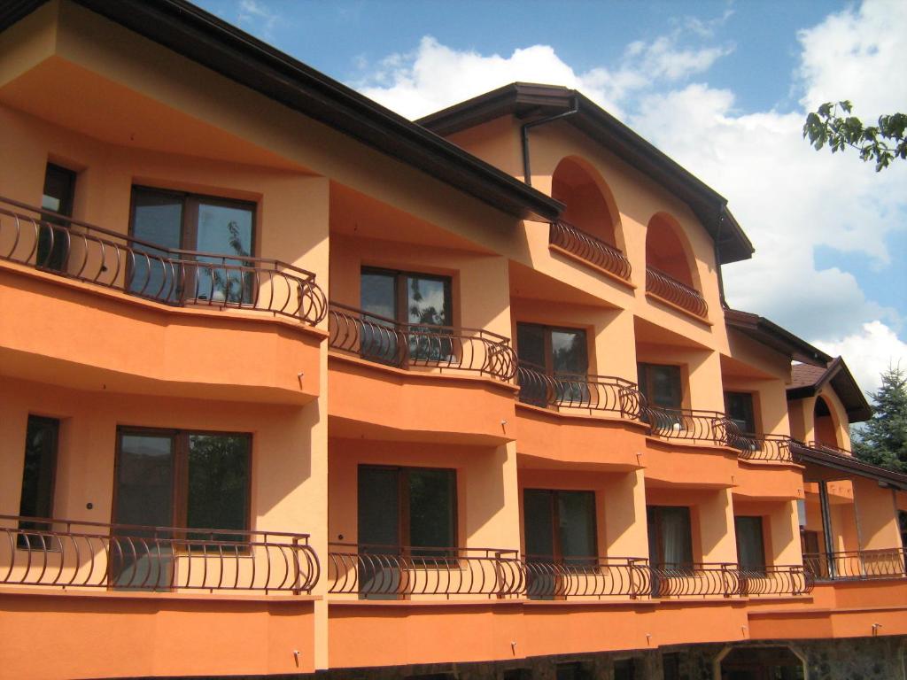 ein orangefarbenes Gebäude mit Balkon an der Seite in der Unterkunft Family Hotel Emaly Green in Saparewa Banja