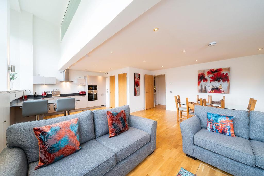 a living room with two blue couches and a kitchen at Whinny Brae in Broughty Ferry