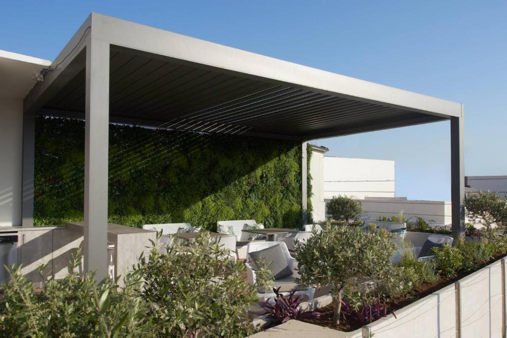 une terrasse couverte avec des chaises blanches et des plantes dans l'établissement 7Rizes Luxury Living, à Héraklion