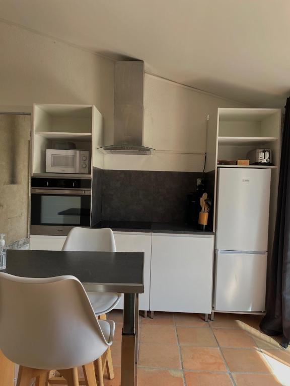 - une cuisine avec des appareils blancs, une table et des chaises dans l'établissement Maisonzen, à Pugnac